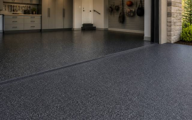 Garage floor covered wall to wall in dark speckled rubber surfacing.