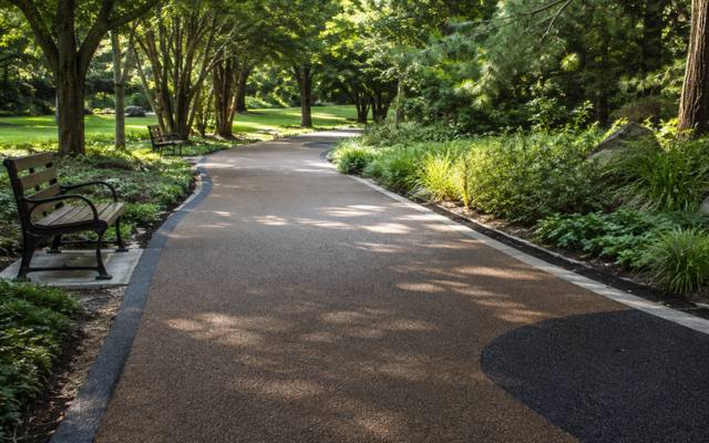 A curving path of rubber surfacing running through a wooded park.