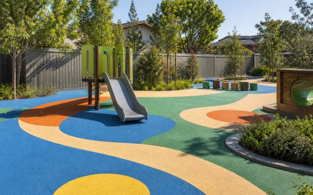 Daycare play area with a slide standing on colourful rubber safety surfacing.